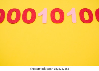 A top view of red and pink binary codes on a bright yellow surface