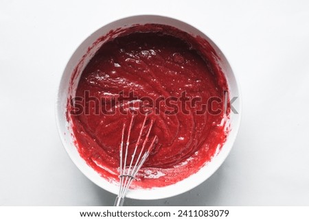 Top view of Red velvet cake batter in a white ceramic mixing bowl, process of making valentines cake, red cake batter in a bowl