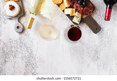 Top view of Red wine bottle, White wine bottle and charcuterie board with different snacks for wine. Different type of cheese, grapes, cured meat and crackers. Wine and tapas background , copy space - Powered by Shutterstock