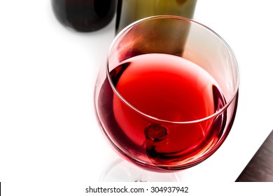 Top Of View Of Red Wine Glass Near Wine Bottles On White Table