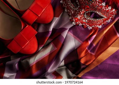 A Top View Of Red Woman's Shoes And Mask Located On A Colorful Pleated Woman’s Shawl In Horizontal Format