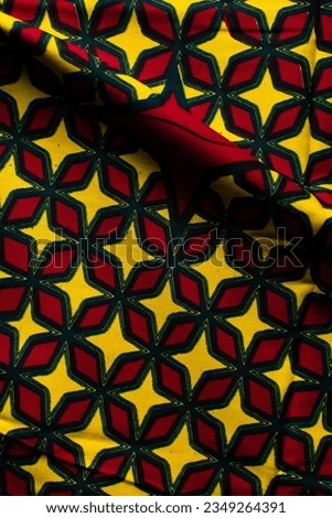 top view of red and yellow ankara fabric, flatlay of nigerian wax cloth, rumpled red and yellow ankara material