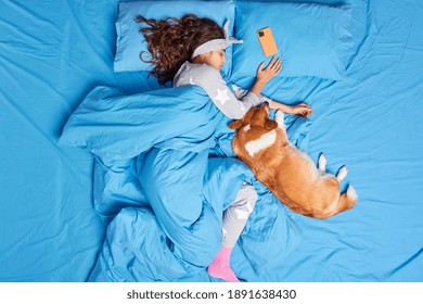 Top View Of Relaxed Beautiful Woman With Long Dark Hair Sleeps At Cozy Bedroom Enjoys Spending Time With Favorite Pet Sees Pleasant Dreams During Night Sleep Dressed In Nightwear. Napping Concept