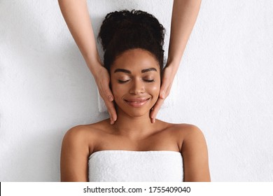 Top view of relaxed black young woman having facial massage over white background