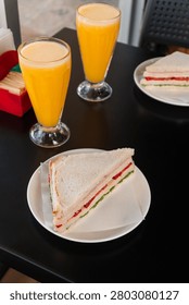 Top view of a restaurant table with vegetable sandwiches and orange juice.