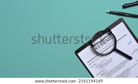 Top view resumes of applicants and magnifying glass on green background. Job search concept