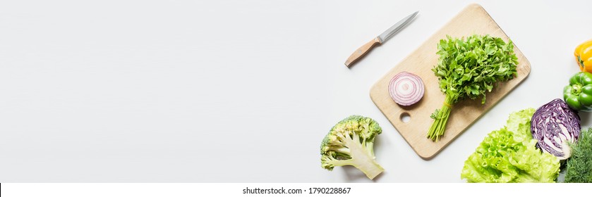 top view of ripe vegetables near wooden cutting board with parsley and onion on white surface, panoramic shot - Powered by Shutterstock