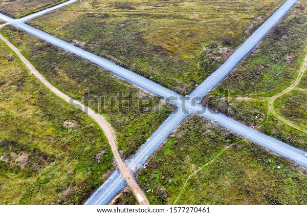 Top view of a road intersection. Intersection of\
dirt and asphalt roads