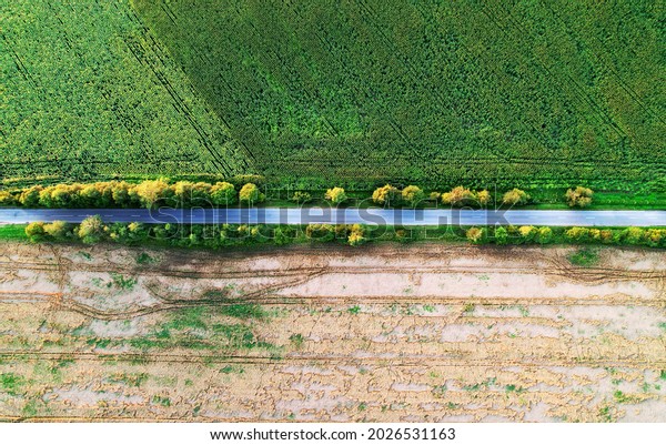 Top view of road near agricultural field. Road\
through the green plant. Ecosystem and environment concept at\
highway. Aerial view of countryside route. Ecological path\
background. Tourist way.