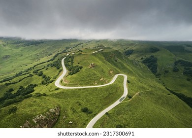 Top view of the road serpentine in the mountains in the background of cloudy sky. Aerial photo of landscape - Powered by Shutterstock