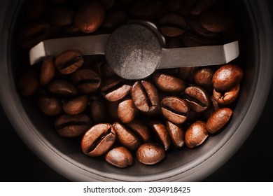 Top view of roasted aromatic coffee beans lying between the blades in a coffee grinder. The process of making coffee. Macro. - Powered by Shutterstock