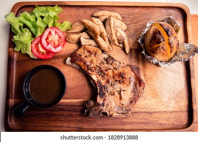 Top view of roasted kurobuta pork chop with sauteed mushroom, potato wedges and black pepper gravy sauce on wooden cutting board - Powered by Shutterstock