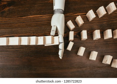 top view of robotic hand preventing wooden blocks from falling on desk