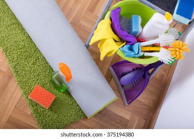 Top View Of Rolled Green Carpet On Parquet With Sponge And Cleaning Supplies