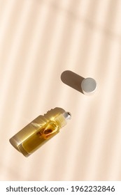 Top View Of Roller Bottle On Striped Shadow Beige Background.