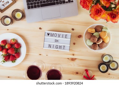 Top View Romantic Movie Night Concept. Movie Night Message On Light Board, Laptop, Candles, Flowers, Macaroons, Berries, And Two Glasses With Wine For Belovers. Cozy Holiday Plans For Valentine's Day