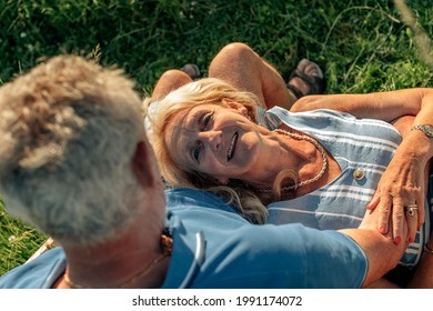 Top View Of Romantic Senior Couple - Woman Lying Down On Husband Legs - Elderly People Bonding - Family In Third Age - Outdoor Sunset Light 