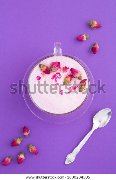 Top view of rose moon milk in glass cup on the\
violet surface. Location\
vertical.