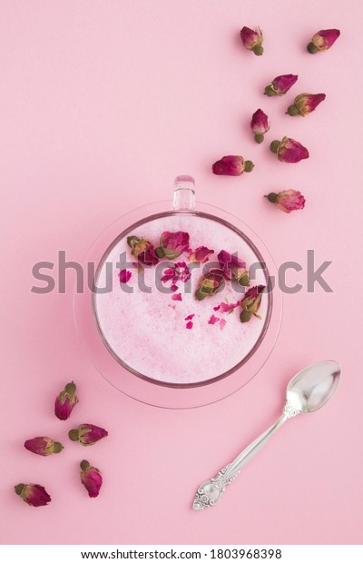Top view of rose moon milk in glass cup on the\
pink surface. Location\
vertical.