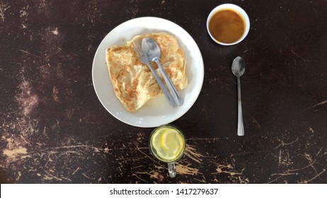 Top View Of Roti Canai, Lemon Drink And Curry 