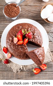 Top View Of Round Baked Chocolate Sponge Cake With Strawberry On Wooden Table