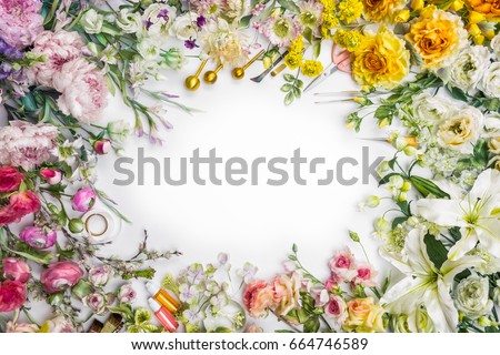 Top view of round frame with decoration artificial flowers, branches, leaves, petals, instruments and paint. isolated on white background.