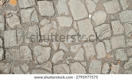 Top view of rustic, weathered paving stones texture with dirt and cracks. Old stone pavement background