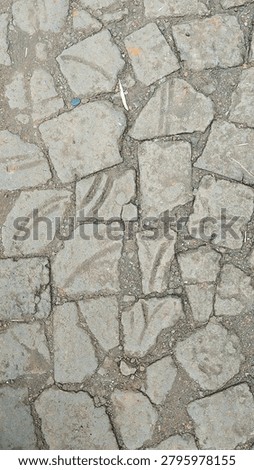 Top view of rustic, weathered paving stones texture with dirt and cracks. Old stone pavement background
