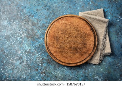 Top view of rustic wooden cutting board on blue concrete background with copy space