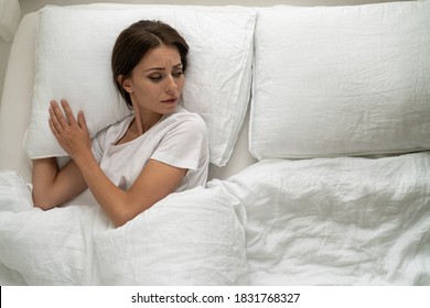 Top View Of Sad Woman Lying In Bed Alone, Looking To Aside At An Empty Pillow, Depressed, Feeling Lonely After Quarrel With Her Boyfriend Or Divorce, Break Up. Husband Left Home. Relationship Trouble.