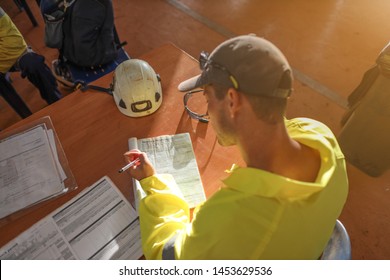 Top view of safety work administrator setting on the chair writing Job Safety Hazard control risk assessment (JHA) working at height permit prior commence work of each task construction site   