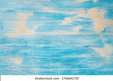 Top view of sandy beach and marine blue planks pier. Background with copy space and visible sand and wood texture.