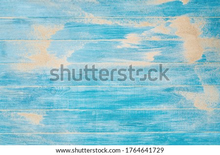 Top view of sandy beach and marine blue planks pier. Background with copy space and visible sand and wood texture.