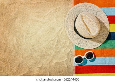 Top View Of Sandy Beach With Towel Frame And Summer Accessories. Background With Copy Space And Visible Sand Texture. Right Border Made Of Towel