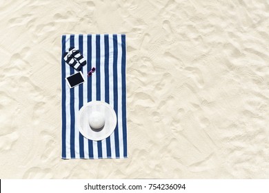 Top View Of Sandy Beach With Towel Frame And Summer Accessories. Background With Copy Space And Visible Sand Texture.