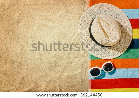 Top view of sandy beach with towel frame and summer accessories. Background with copy space and visible sand texture. Right border made of towel