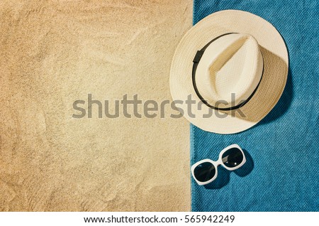 Top view of sandy beach with towel frame and summer accessories. Background with copy space and visible sand texture. Right border made of towel