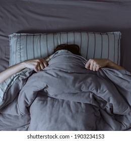 Top view of scared woman in bed covering her face with blanket. - Shutterstock ID 1903234153