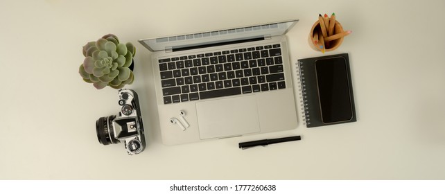 Top View Of Scene Creator With Laptop, Camera, Stationery And Decoration On White Desk 