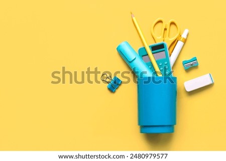 Top view of school blue jar with school supplies with space for text over yellow background. Back to school concept