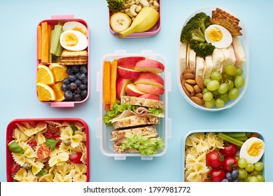 Top view of school lunchboxes with various healthy nutritious meals on blue background