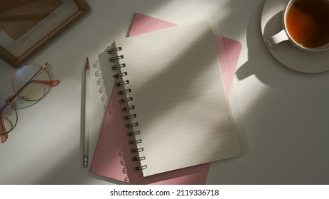 Top View Of School Notebook With Blank Cover Page With Tea Cup, Glasses On White Background. Flat Lay, Creative Feminine Workspace Office.