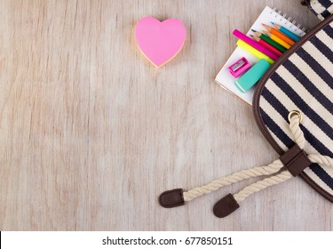 Top View Of School Supplies On Wooden Desk. Heart Shaped Stickers Beside Bag For Your Text