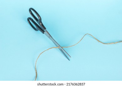 Top View Of Scissors Cutting The Thread. Minimal Business Concept.