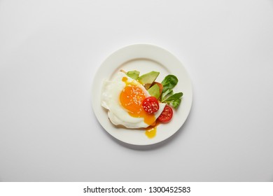 top view of scrambled egg with cherry tomato and avocado in plate on grey background