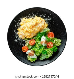 Top View Of Scrambled Eggs With Salad On Black Plate Isolated On White Background. Healthy Breakfast.