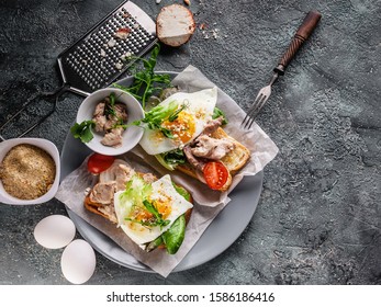 Top View Sea Food Sandwich. Cod Liver, Fresh Lettuce, Pea Sprouts, Tomatoes And Fried Eggs. Healty And Tasty Breakfast On A Cutting Wooden Board.