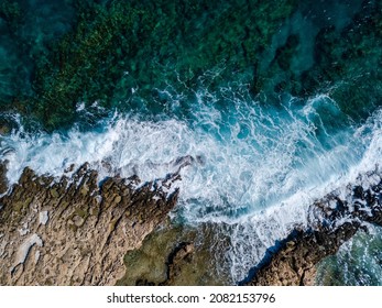 Top view of sea waves crashing of rocky coastline