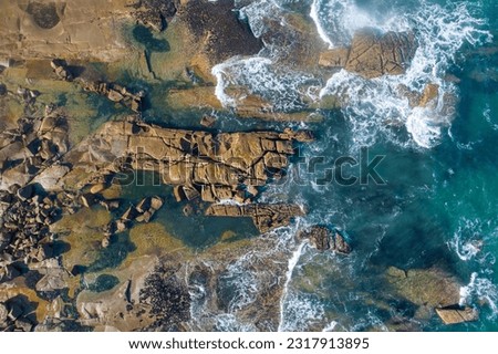 Top view of sea waves crashing on a rocky shore, aerial shot