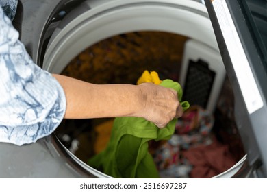 Top View, Selective focus hands of senior woman loading clothes into washing machine to laudry - Powered by Shutterstock